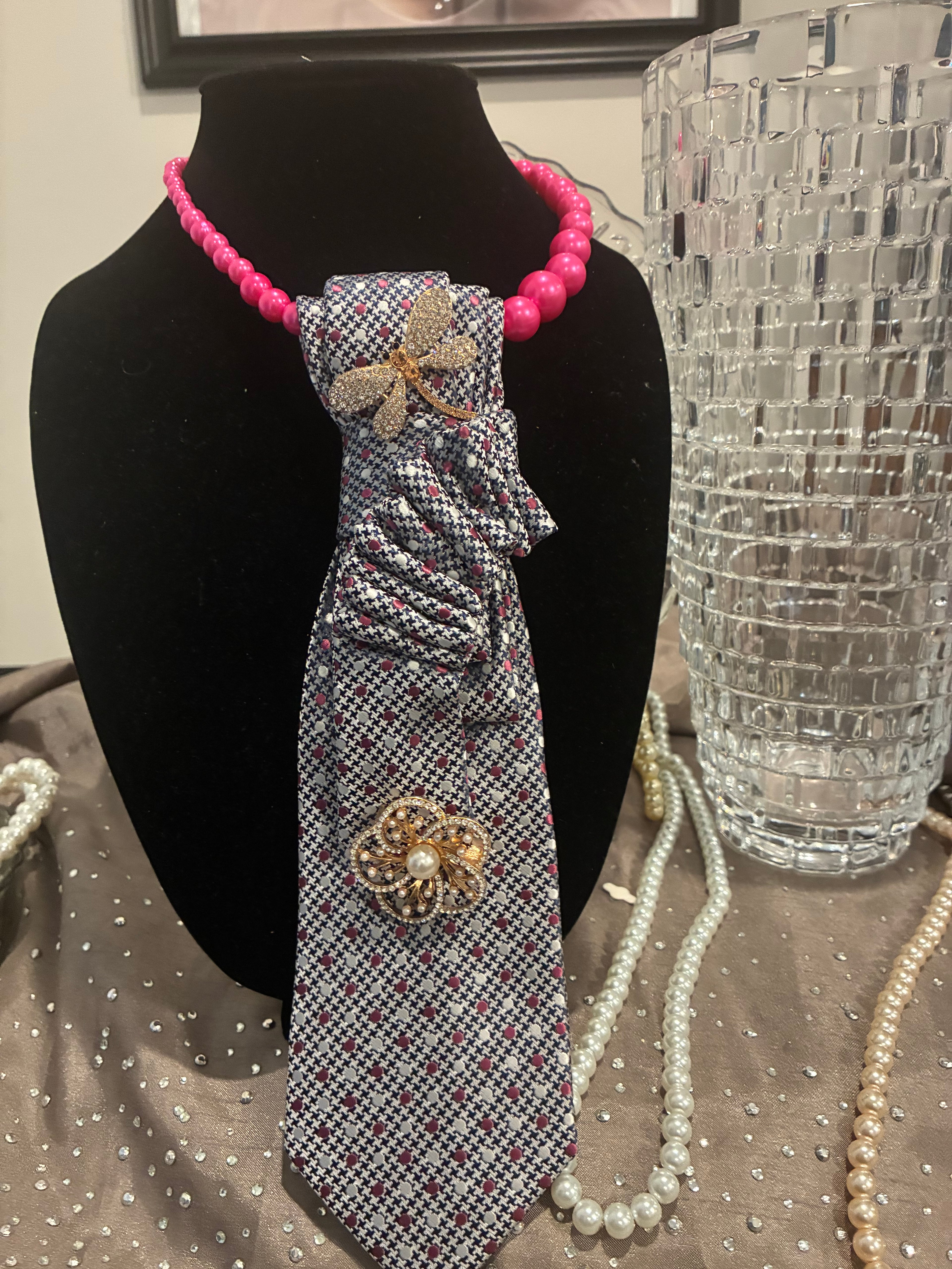 A novelty tie featuring a gray and white micro check pattern, gold butterfly broach and rhinestone flower broach 